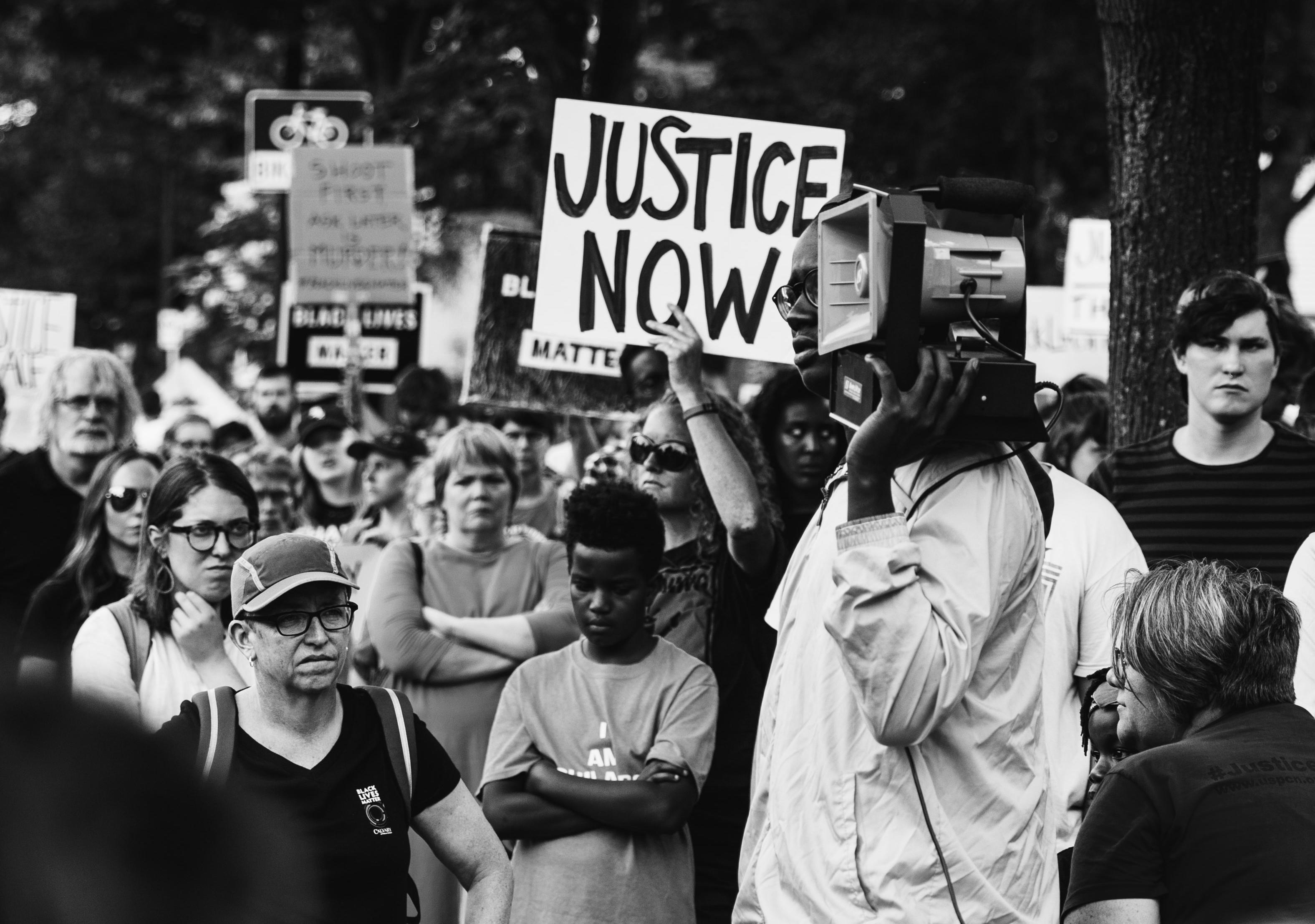 Protests in Minnesota. Woman holding a sign saying "Justice Now."