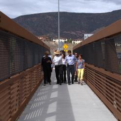 Karen walking across a bridge with community members.