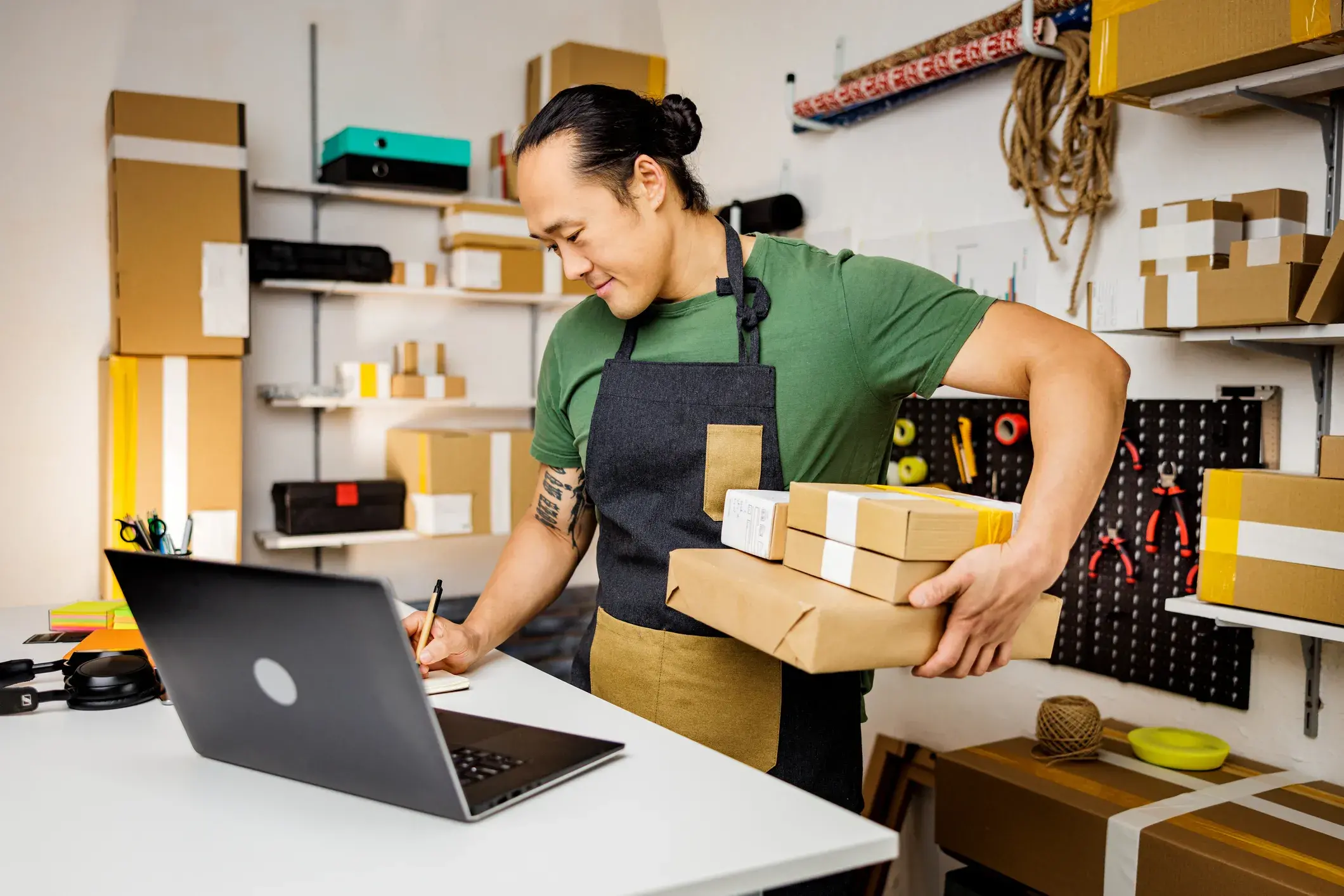 Man Working holding boxes and writing in front of computer