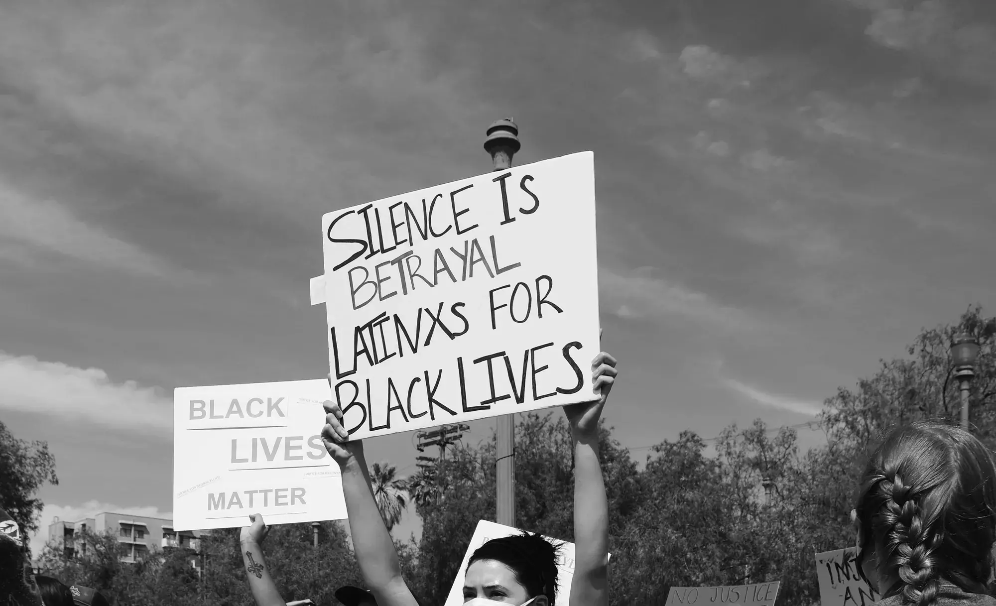 Person holding sign, "Silence is betrayal for Latinx for Black lives"